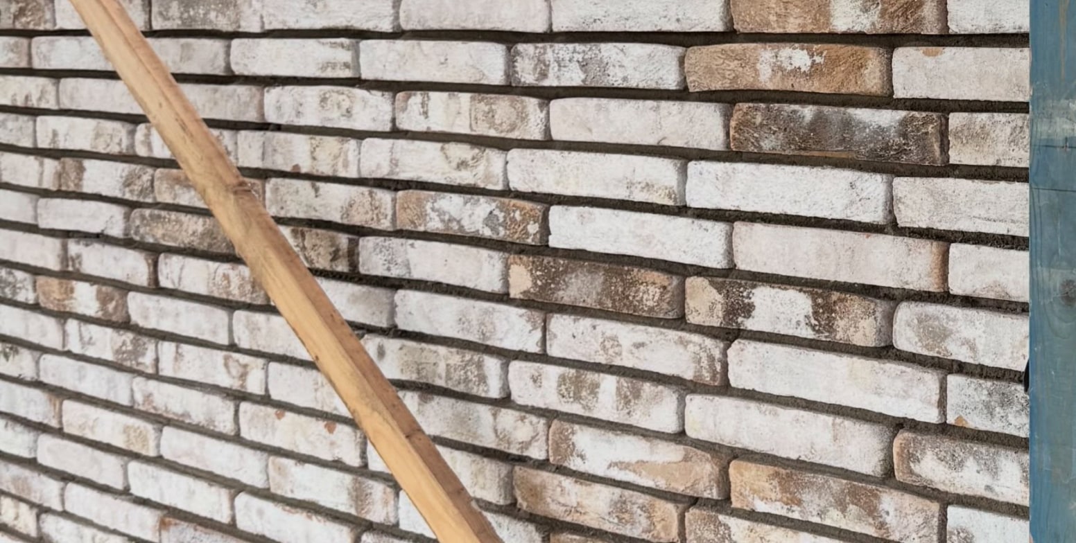 Vers gemetselde muur van witgrijze steen in de steiger, met een houten schoor ervoor